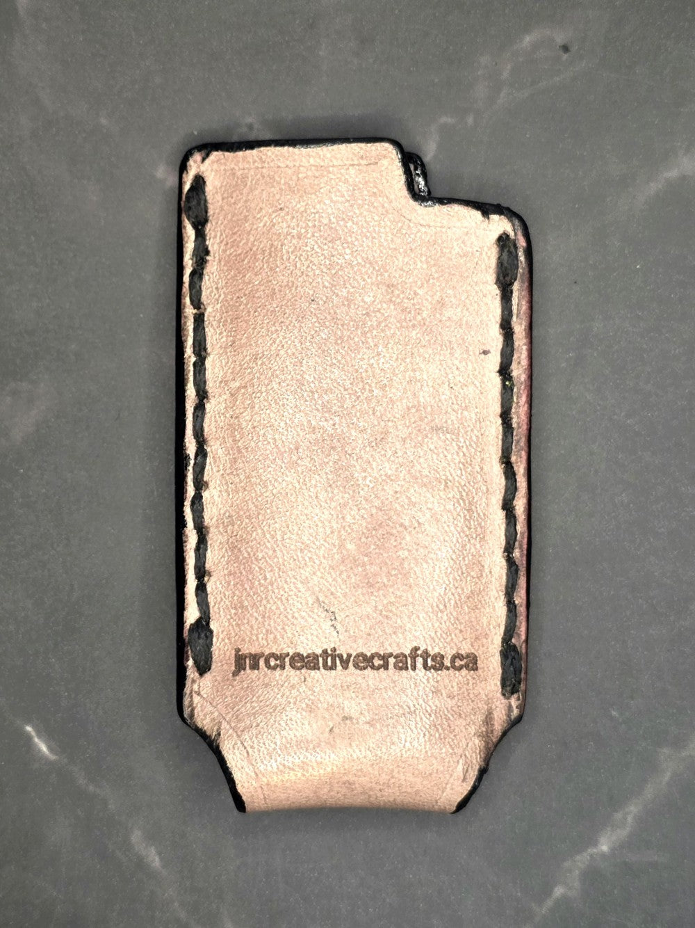 Picture of a light brown veg-tan leather lighter case for bic lighters with skull and crossbones stamped into it. Crafted in Canada by JnRcreativeCrafts.
