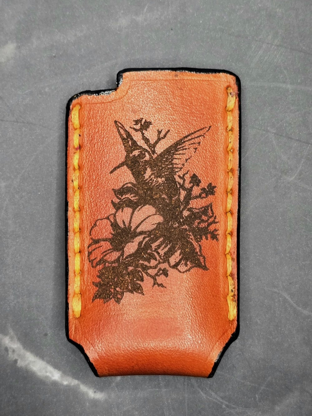 Picture of a Canadian Crafted veg-tan leather lighter case for bic lighters with a picture of a hummingbird laser engraved on it. Made in Canada.