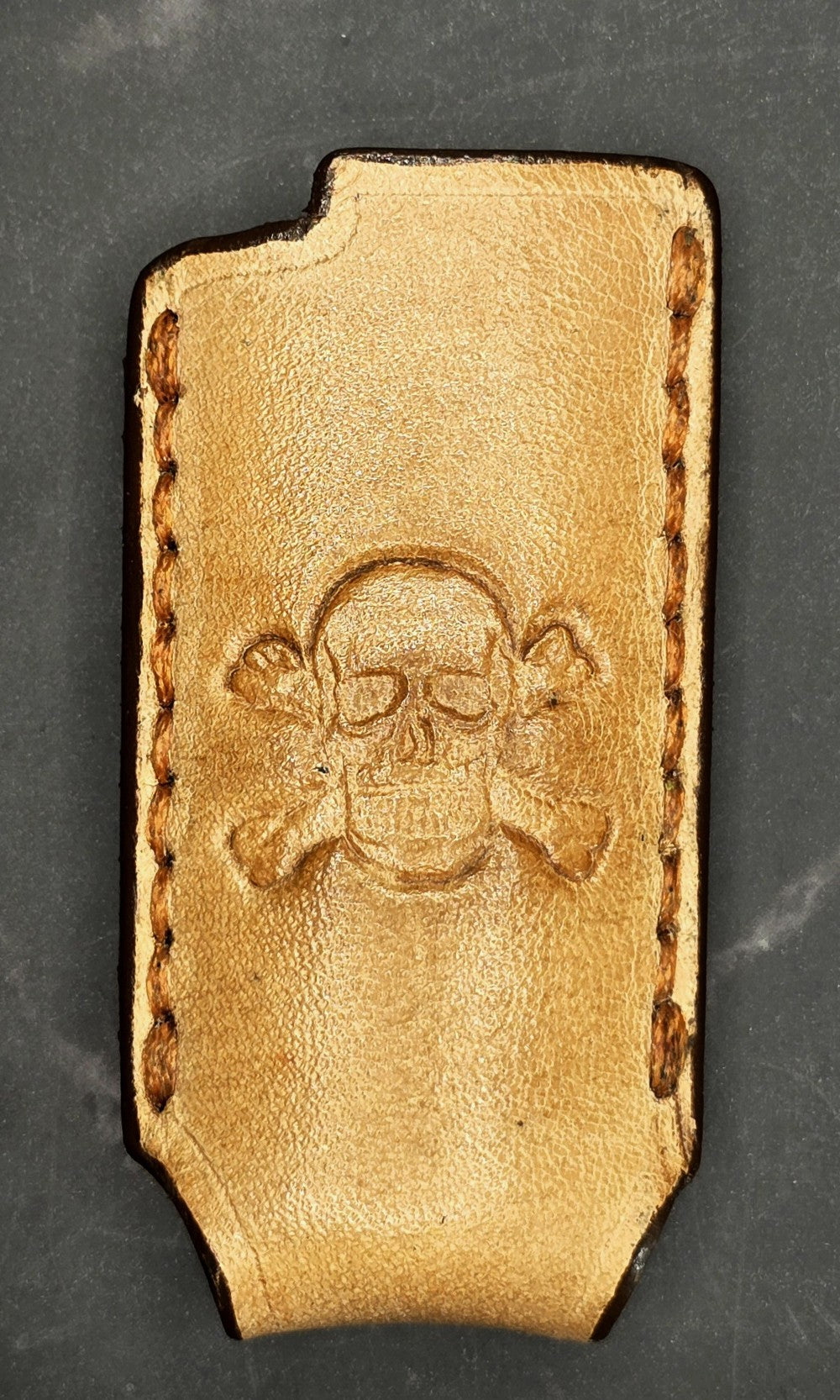 Light brown vegetable tanned leather lighter case for bic lighters with a skull and crossbones stamped into it.