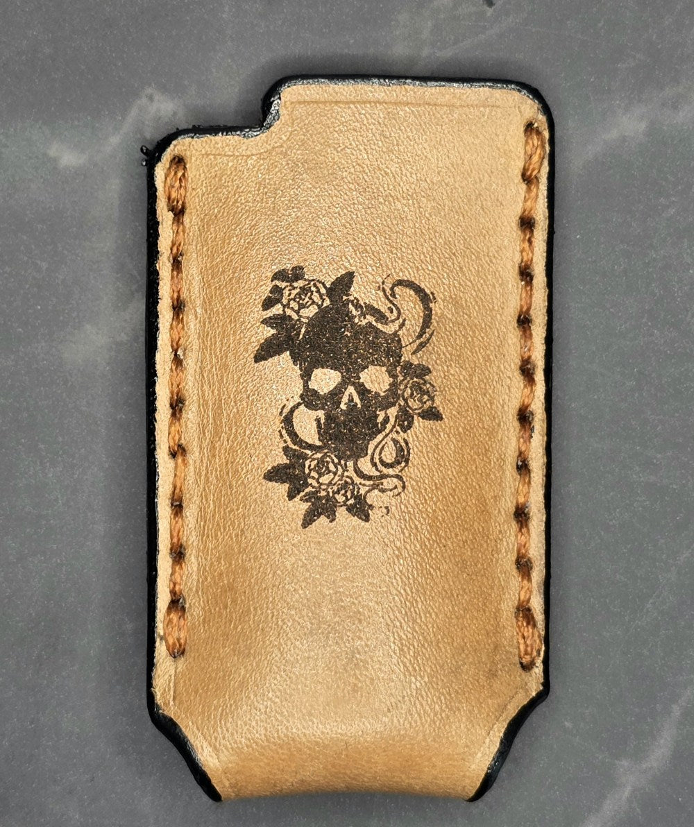 Light brown vegetable tanned leather lighter case for bic lighters with a skull and roses laser engraved on it.