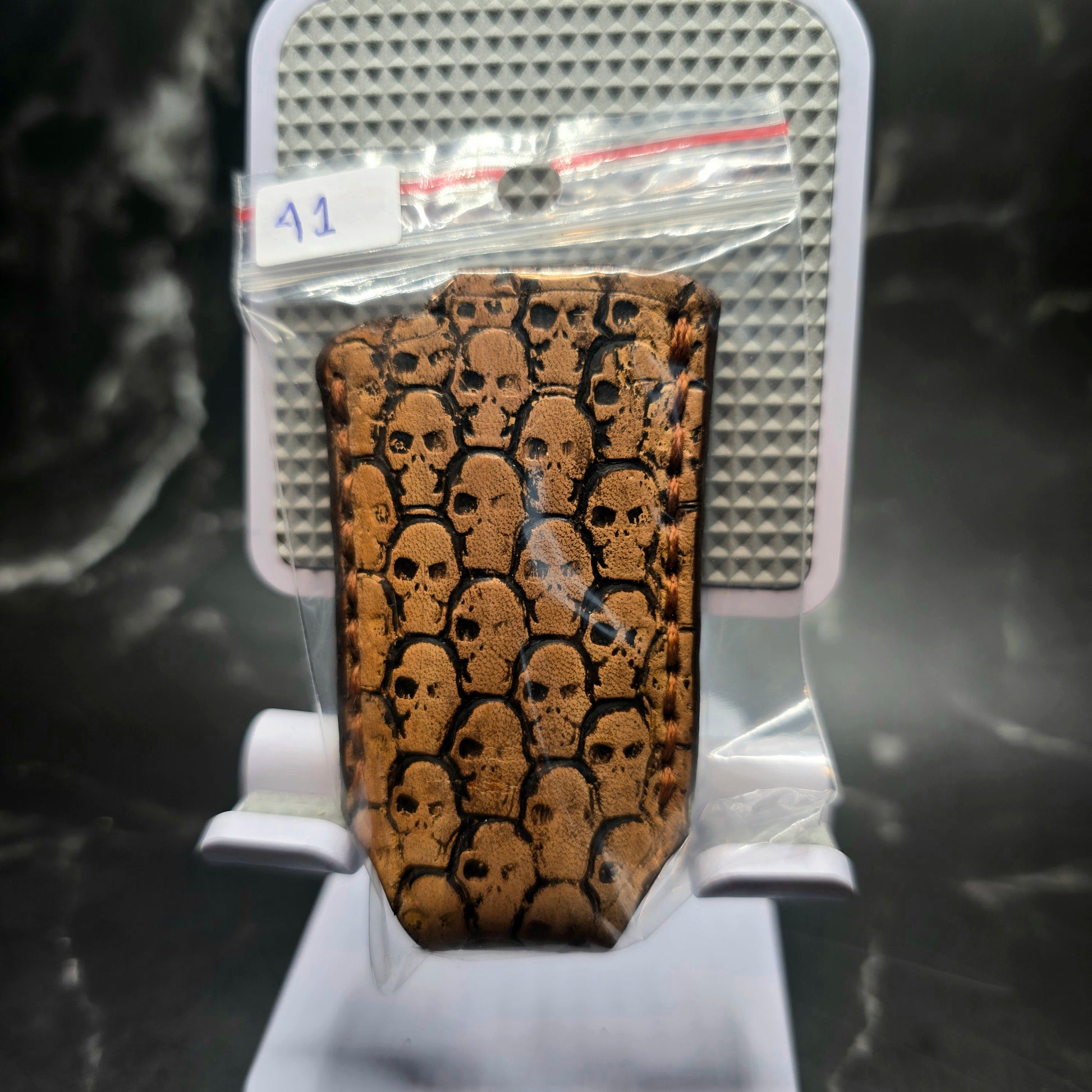 Light brown vegetable tanned leather lighter case for bic lighters with skulls stamped into it in retail package.