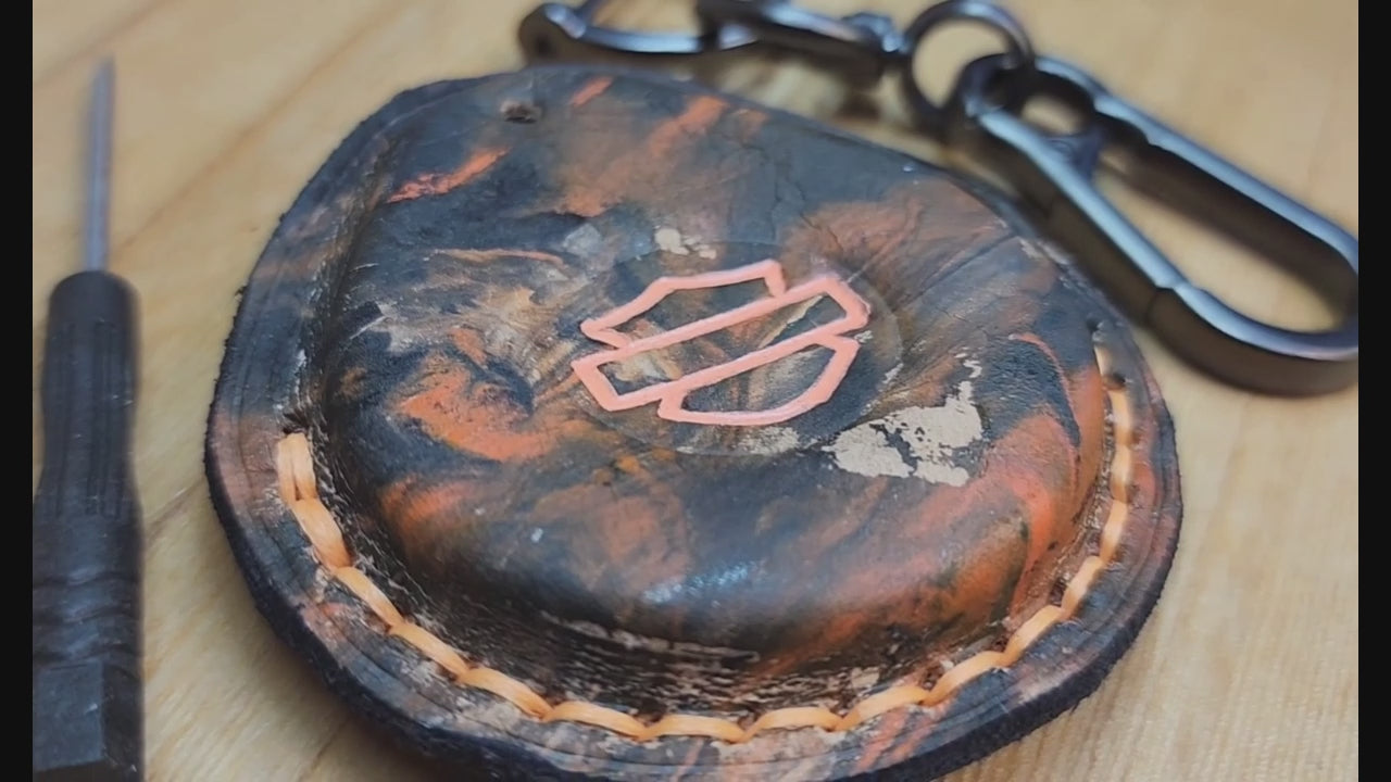 Video of a camo style black and orange leather Harley Davidson key fob case with keychain and screwdriver. Démonstration vidéo montrant un porte-clés Harley Davidson inséré dans un étui en cuir pour porte-clés.