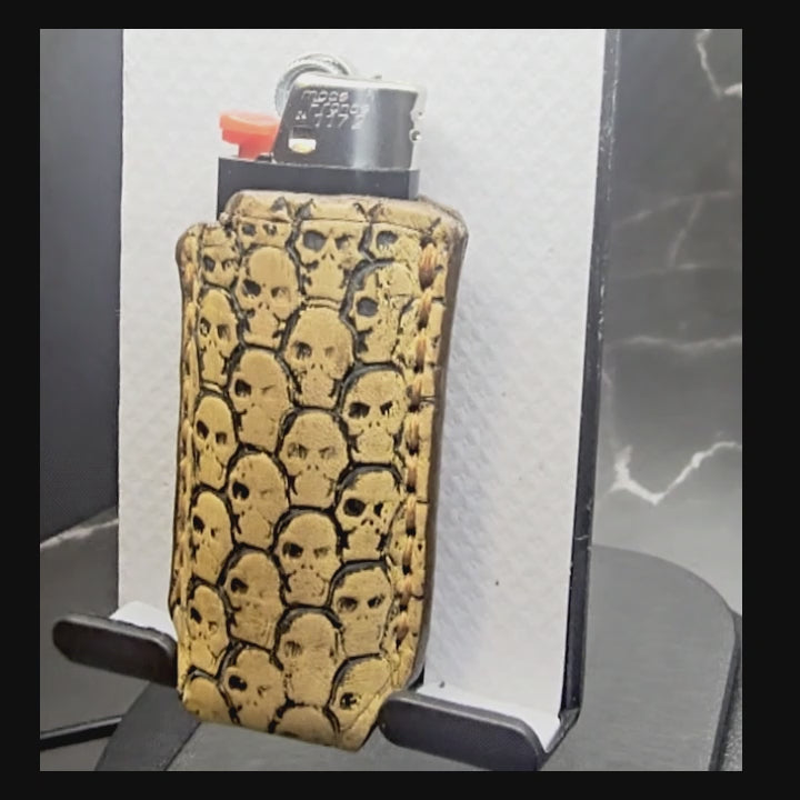 Video of a light brown vegetable tanned leather lighter case for bic lighters with skulls stamped into it.