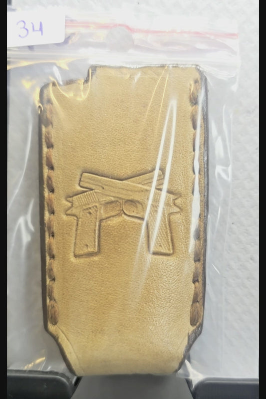 Video of a light brown veg-tan leather Bic lighter case with a pair of handguns stamped into it.