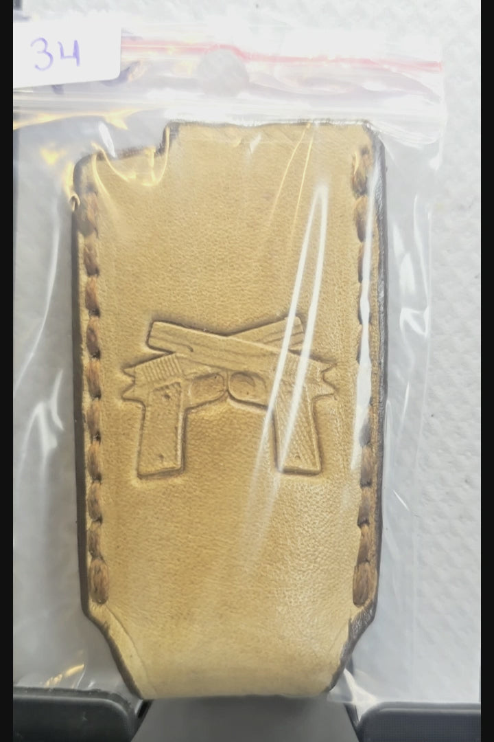 Video of a light brown veg-tan leather Bic lighter case with a pair of handguns stamped into it.