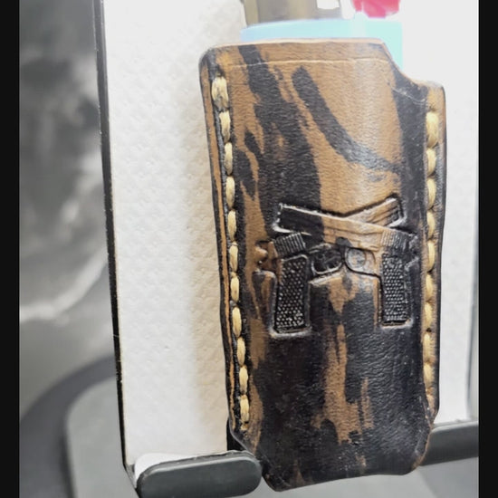 Video of a black and brown camo-style veg-tan leather lighter case for bic lighters with a pair of handguns stamped into it.