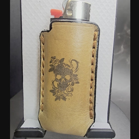 Video of a light brown vegetable tanned leather lighter case for bic lighters with a skull and roses laser engraved on it.