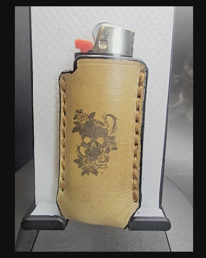 Video of a light brown vegetable tanned leather lighter case for bic lighters with a skull and roses laser engraved on it.